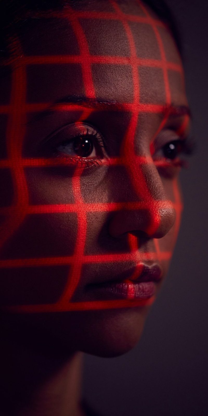 Facial Recognition Technology Concept As Woman Has Red Grid Projected Onto Face In Studio